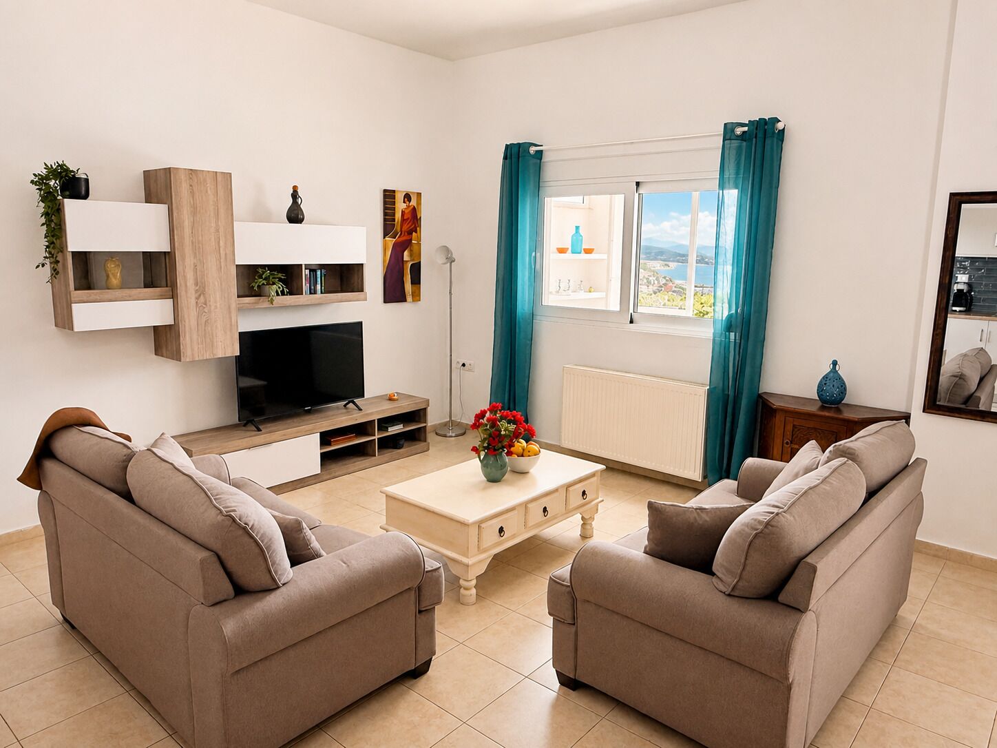 A living room with a TV, two sofas, a coffee table, and a window with curtains.
