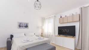 A modern hotel room with a bed, a TV, a desk, and a bench. - Villa Aurora with private pool (Tertenia)