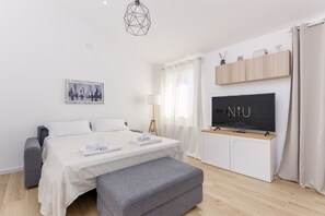 A modern hotel room with a bed, a TV, a desk, and a bench. - Villa Aurora with private pool (Tertenia)