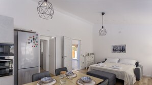 A modern kitchen with a refrigerator, oven, and dining table set with plates and a water jug. - Villa Aurora with private pool (Tertenia)