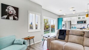 A modern living room with a sofa, a small table, and a painting on the wall. - Casa Solara - A Ryson Property (Palm Springs)