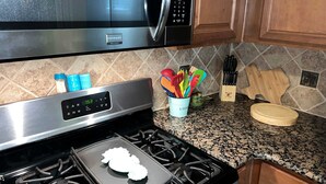 A kitchen with a microwave, stove, and utensils. - Surf + Strand Dual-unit Stay (Galveston)