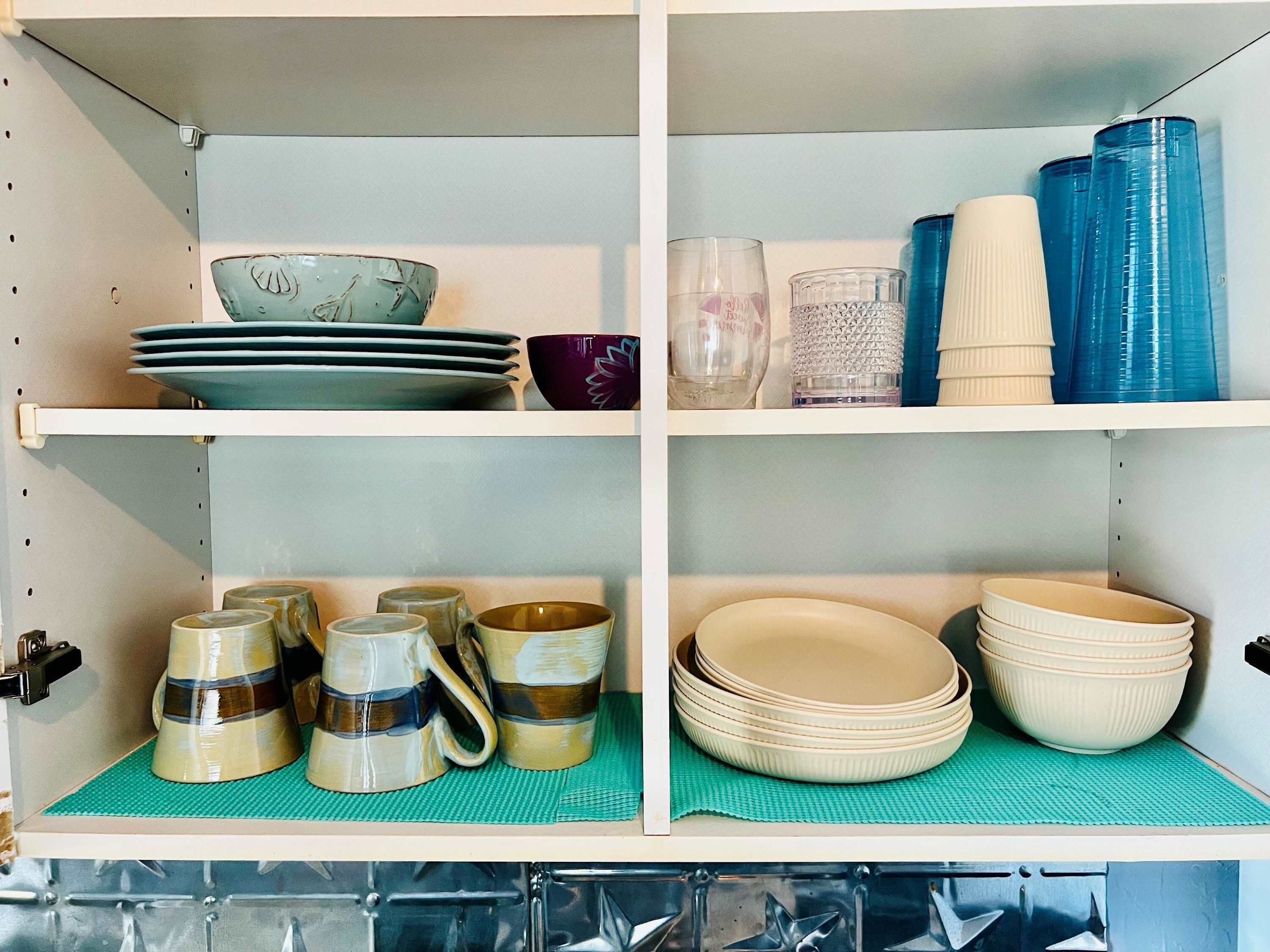 A kitchen with shelves holding plates, bowls, and cups.