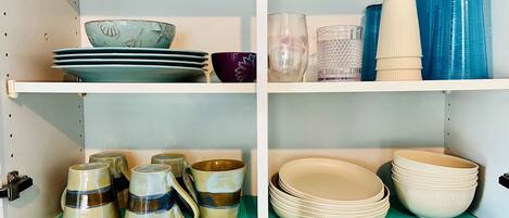 A kitchen with shelves holding plates, bowls, and cups.