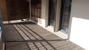 A wooden deck with a metal grill and a sliding glass door.