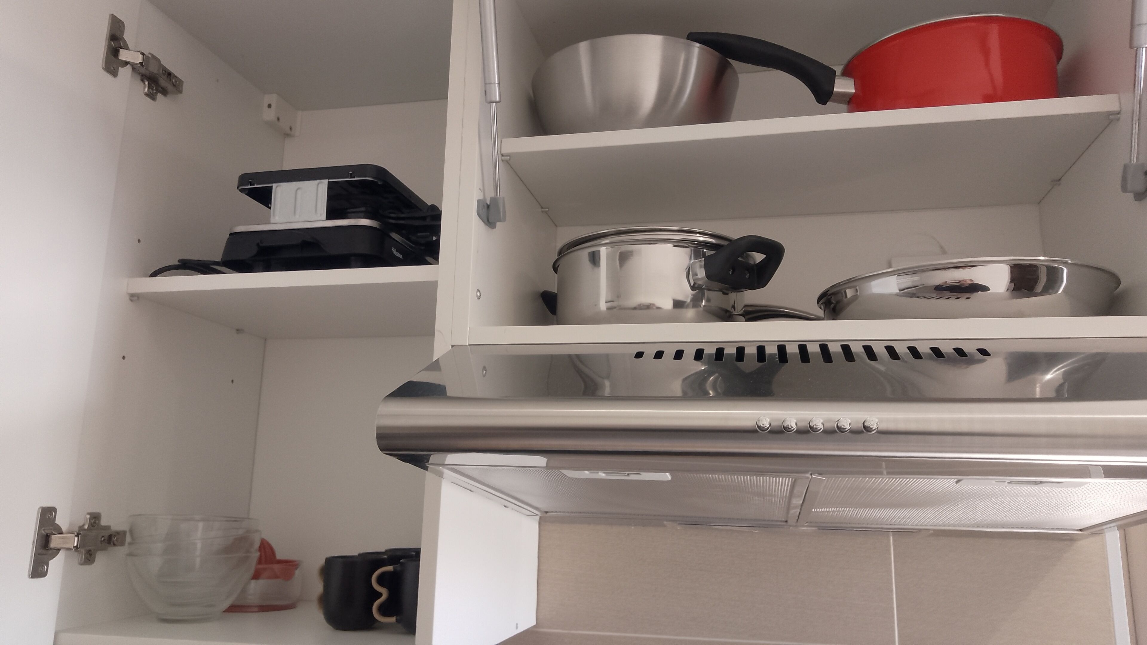 A kitchen with stainless steel appliances, including a stove and oven, and shelves with pots and pans.