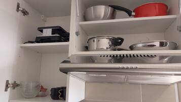 A kitchen with stainless steel appliances, including a stove and oven, and shelves with pots and pans.