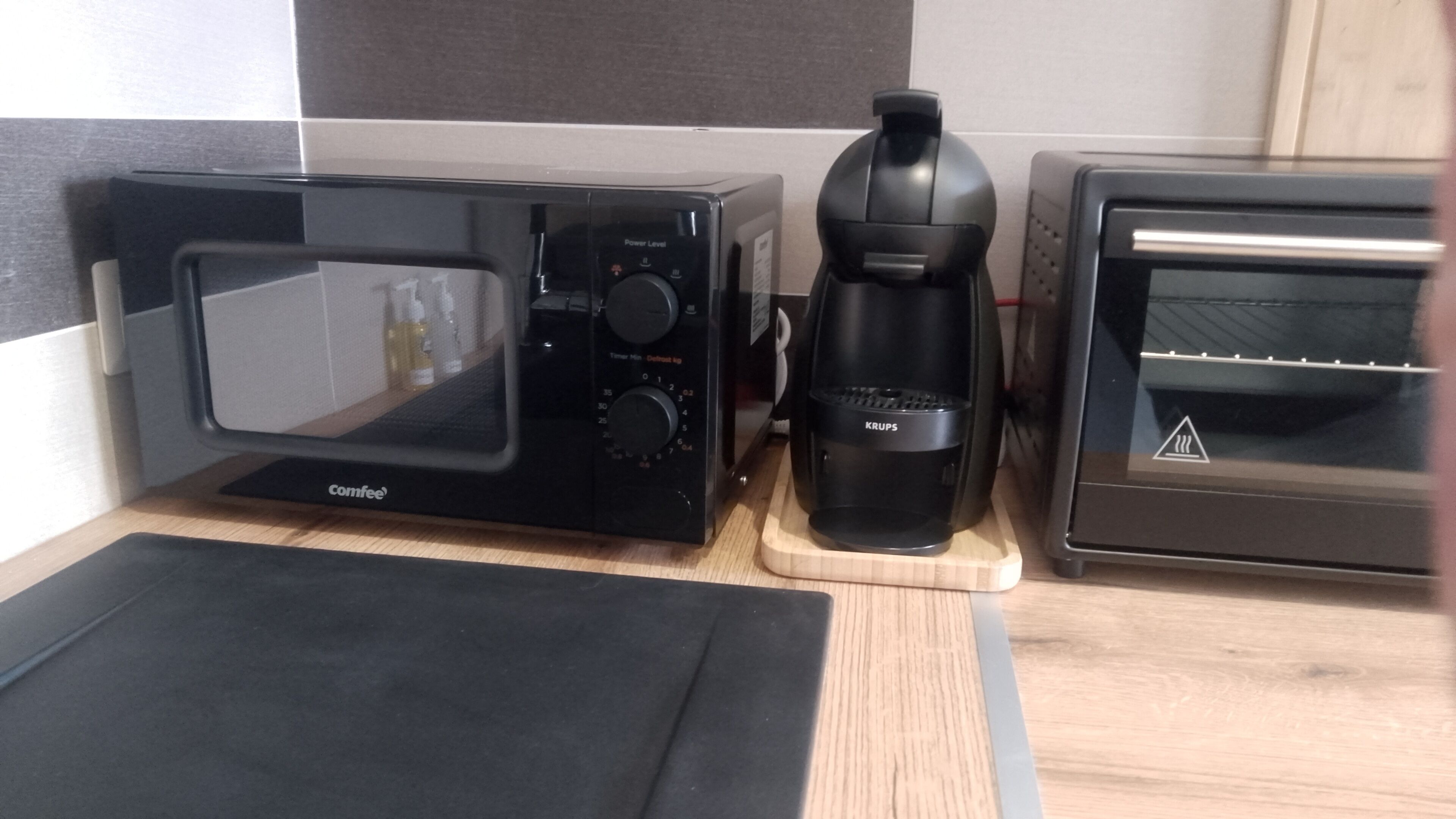 Una cocina con un microondas Comfee, una cafetera Krups y un horno tostador.