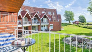 A residential building with a red brick facade, multiple balconies, and a view of a green landscape. - Linda - Balcony with sea view, private beach chair on the beach, swimming pool (Kronsgaard)
