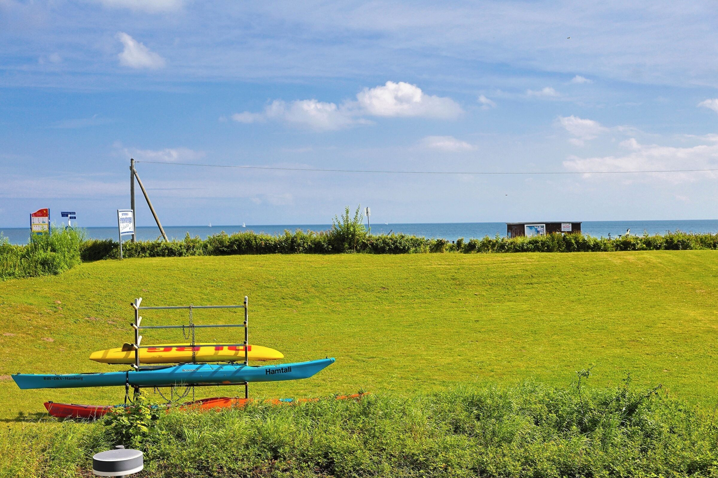 A grassy field with a small building and a body of water in the background.