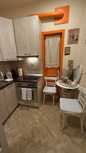 Uma cozinha compacta com fogão, forno e uma pequena área de refeições com mesa e cadeiras.