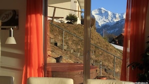 A room with a view of a mountain landscape through a glass door. - swissmountainview - sunny & quiet - terrace, Jacuzzi, view to lake + mountains (Beatenberg)