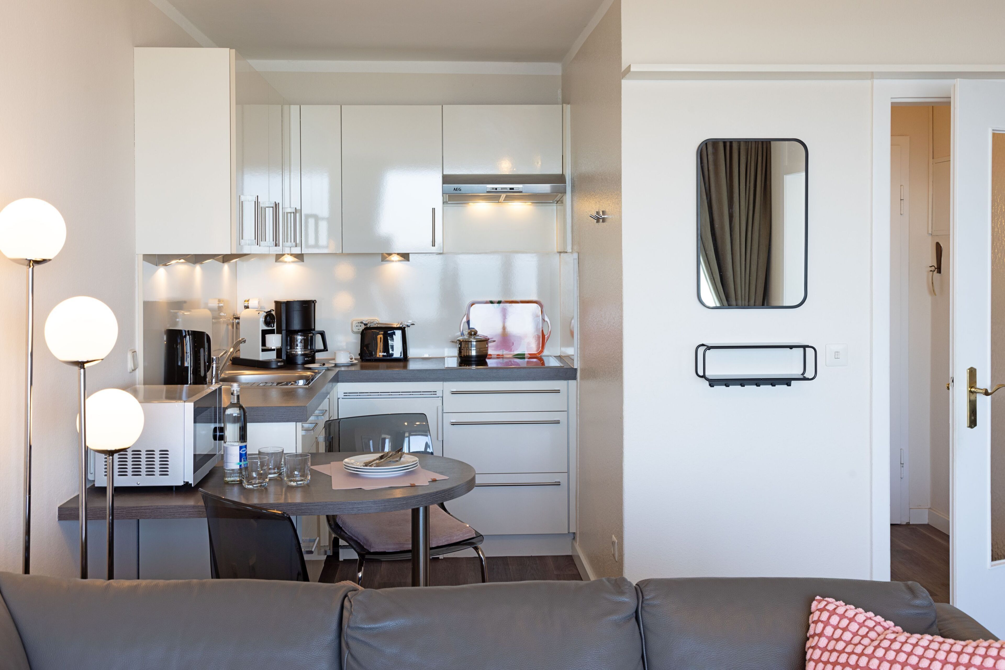 A compact kitchen with modern appliances, a dining area with a round table, and a living space with a sofa.