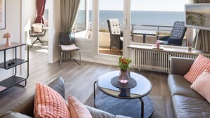 A modern living room with a view of the sea, a round glass coffee table, a sofa, and a chair. - Welcome to the Best View apartment (List auf Sylt)