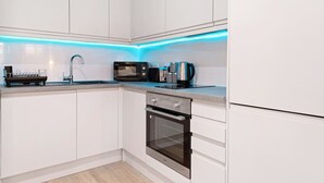 A modern kitchen with white cabinets, a stainless steel oven, a microwave, and a coffee maker. - Comfortable 1 Bed Studio, 10/10 Location (Nottingham)
