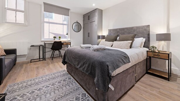 A modern bedroom with a large bed, a desk, and a chair. - Comfortable 1 Bed Studio, 10/10 Location (Nottingham)