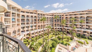 Un hotel de varios pisos con un patio central que cuenta con palmeras y un área de piscina.