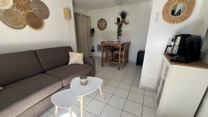Una sala de estar con un sofá marrón, una mesa de centro blanca y un comedor con una mesa y sillas de madera.
