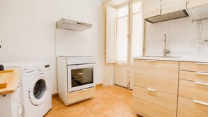 Eine kleine Küche mit Waschmaschine, Backofen und Holzschränken.