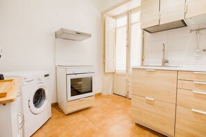 Eine kleine Küche mit Waschmaschine, Backofen und Holzschränken.