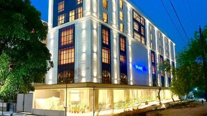 Um hotel de vários andares com fachada moderna, janelas amplas e uma placa visível.
