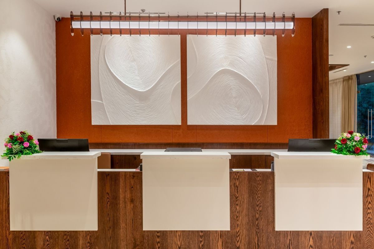 A reception desk with a wooden backdrop and a large abstract artwork above it.