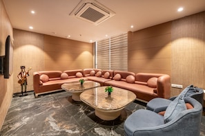 A modern living room with a sectional sofa, two coffee tables, and a small statue. - SkkyLight Lords Inn (Nanded)