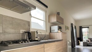 A modern kitchen with a gas stove, a coffee maker, and a microwave on a wooden countertop. - Nature cottage Abcoude - Green Stay Buitenhuis (Abcoude)