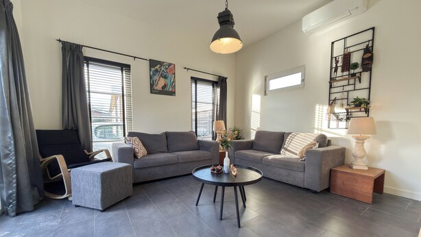 A modern living room with a sectional sofa, a round coffee table, and a lamp on a side table. - Nature cottage Abcoude - Green Stay Buitenhuis (Abcoude)
