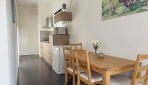 A modern kitchen with wooden cabinets, a built-in oven, and a dining area with a wooden table and chairs. - Nature cottage Abcoude - Green Stay Buitenhuis (Abcoude)