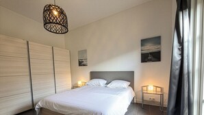 A modern bedroom with a large bed, a wooden wardrobe, a nightstand with a lamp, and a painting on the wall. - Nature cottage Abcoude - Green Stay Buitenhuis (Abcoude)