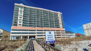 Un hôtel à plusieurs étages, avec une enseigne indiquant l’accès à la plage pour le public.