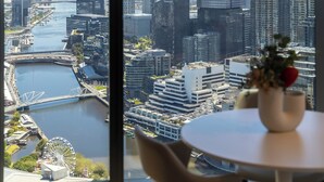 Ein Hotelzimmer in einem Hochhaus mit Blick auf eine Stadtlandschaft, inklusive eines Flusses und eines Riesenrads.