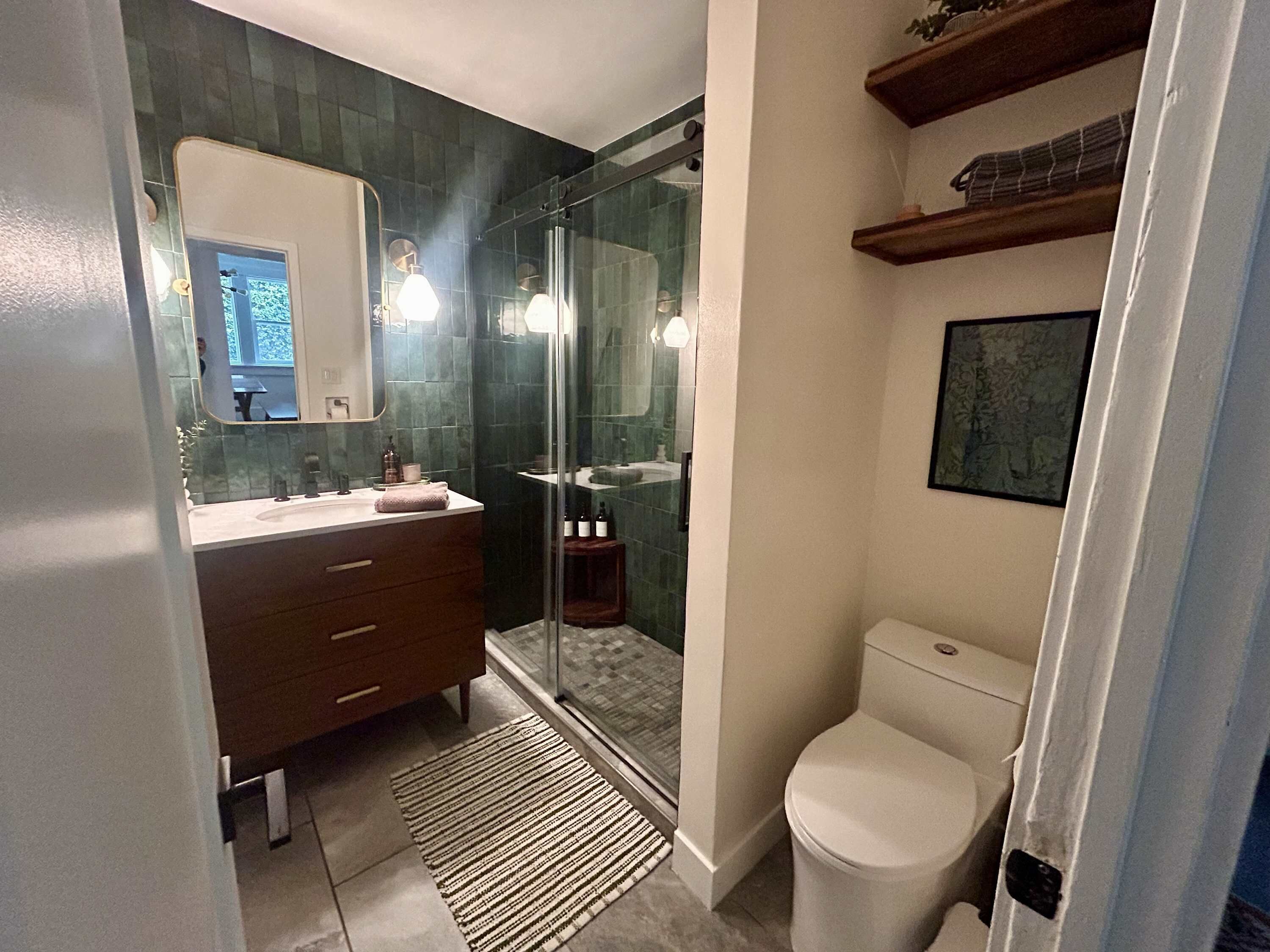 A modern bathroom with a glass shower enclosure, a dark wood vanity, and a white toilet.