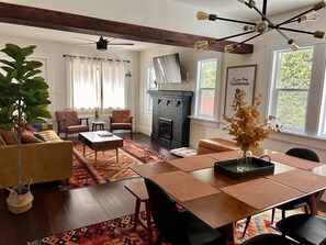 Ein Wohnzimmer mit Kamin, Esstisch und Deckenventilator.