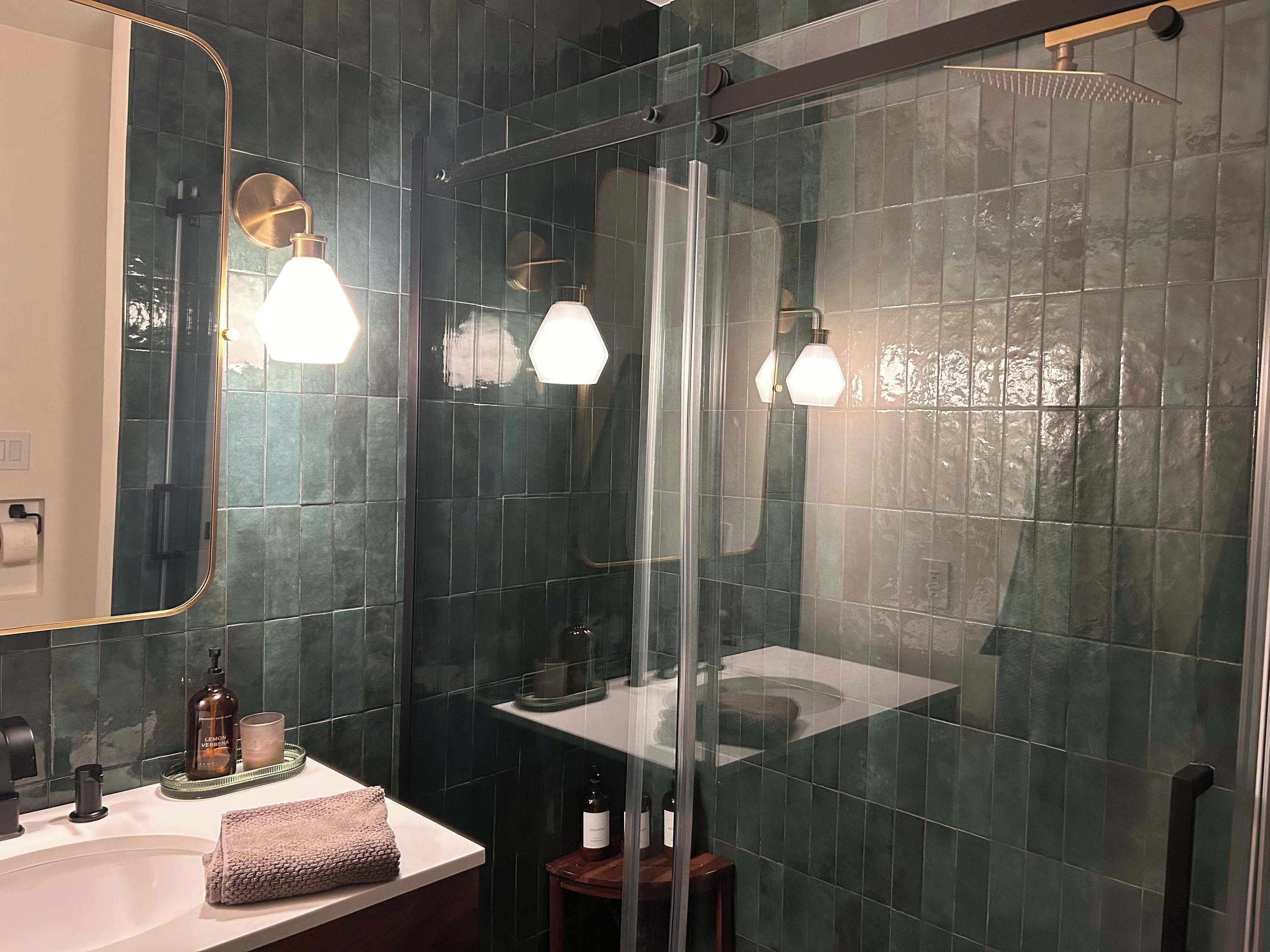 Ein modernes Badezimmer mit Duschkabine aus Glas, einem weißen Waschbecken und einem großen Spiegel.