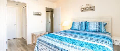 Un dormitorio con una cama, una mesita de noche, una lámpara y un aplique de pared.