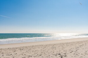 A beach with a clear sky, calm sea, and visible footprints on the sand. - Surf City Hideaway - Cozy 2BR at Tiffany's Motel; Comm. Pool! (Surf City)
