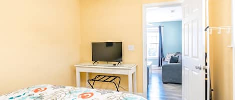 Een slaapkamer met een bed, een bureau met een televisie en een deur naar een andere kamer.