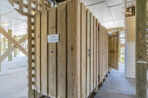 A row of wooden bunk beds with a sign indicating 'Tim's Outdoor Showers.' - Surf City Hideaway - Cozy 2BR at Tiffany's Motel; Comm. Pool! (Surf City)