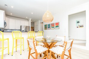 A modern kitchen with white cabinets, a stainless steel refrigerator, and a yellow chair.