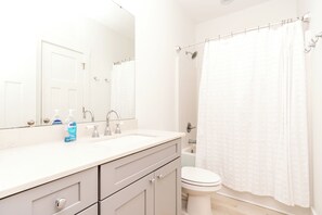 A bathroom with a white sink, two faucets, a mirror, a toilet, and a shower curtain.