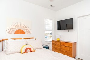 A bedroom with a bed, a dresser, a television, and a window with blinds. - 613A Follow the Sun - Upscale 4 BR Home Surf City; Dogs welcome! (Surf City)