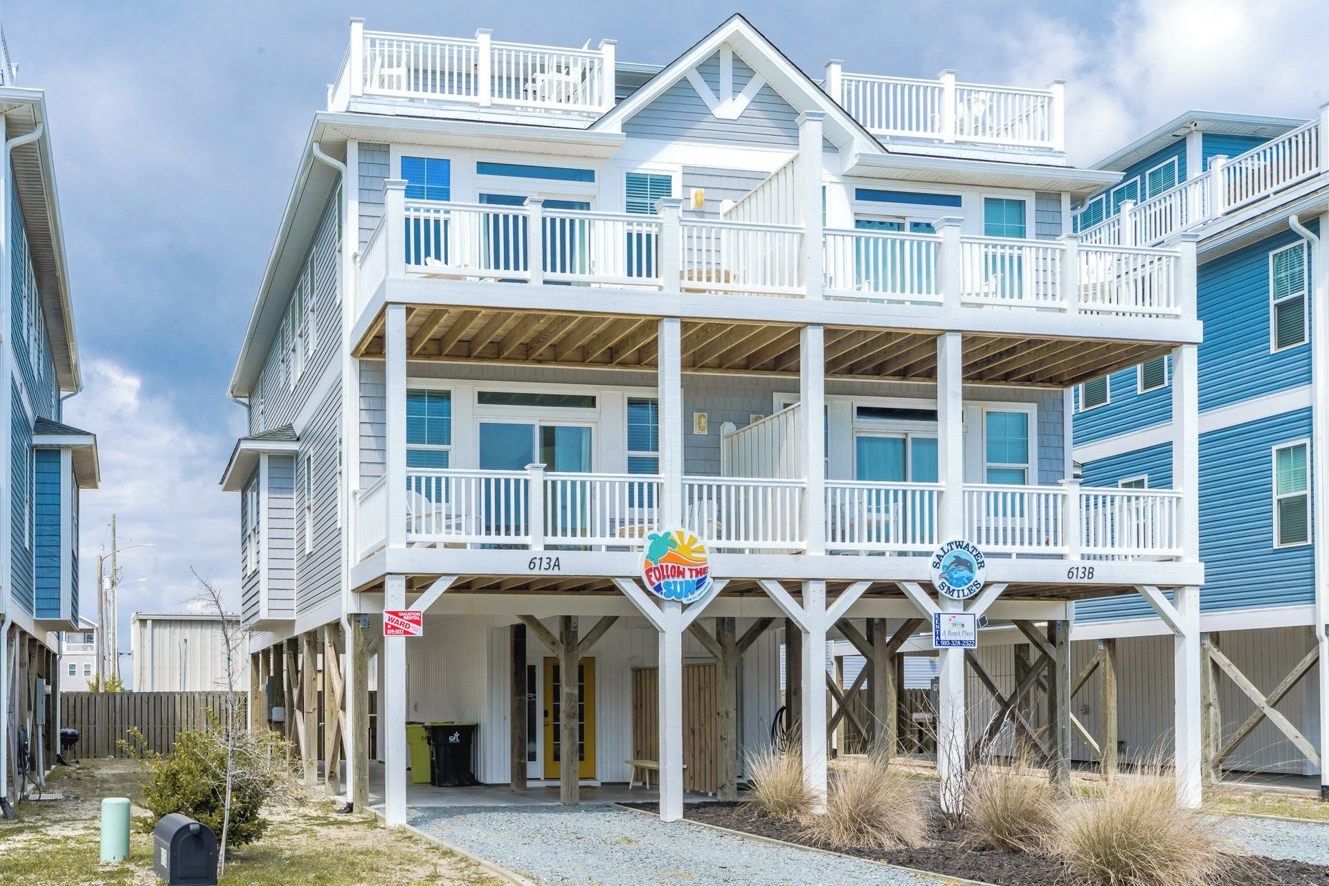 A beachfront property with a two-story building, a covered porch, and a beach access sign.