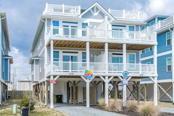 A beachfront property with a two-story building, a covered porch, and a beach access sign.