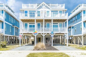 A beachfront hotel with a central balcony, multiple windows, and a sign indicating a beach view.