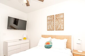 A bedroom with a bed, a TV, a dresser, and wall art. - 613A Follow the Sun - Upscale 4 BR Home Surf City; Dogs welcome! (Surf City)