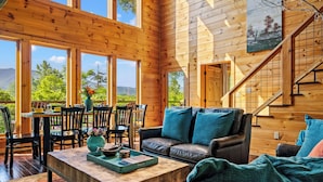 Ein Holzblockhaus-Interieur mit Essbereich, Sofa und Treppe.