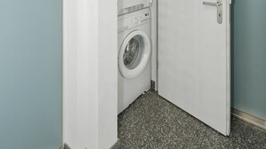 Una sala de lavandería con lavadora, secadora y estanterías.