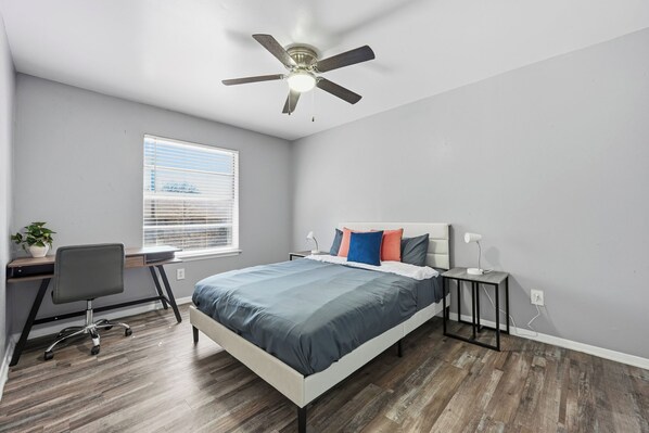A bedroom with a bed, a desk, a chair, a ceiling fan, and a window with blinds. - 2-bedroom with large living area (Denton)